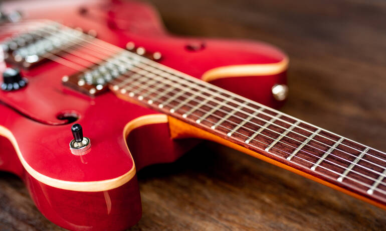 guitare-electrique-rouge-sur-plancher-en-bois.jpg